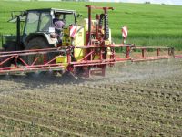 Traktor mit Aufsattelspritze bei der Pflanzenschutzmaßnahme auf dem Acker